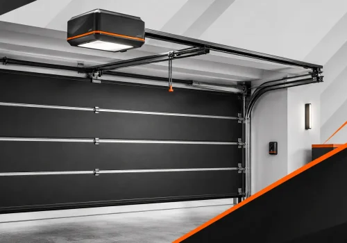 Automatic garage door opener mounted above a black sectional door, showing rails, lighting, and control hardware.