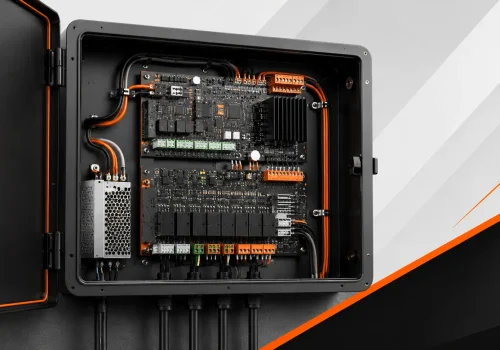 Open automation control panel with circuit boards, terminal blocks, wiring, and power supply in a black enclosure.